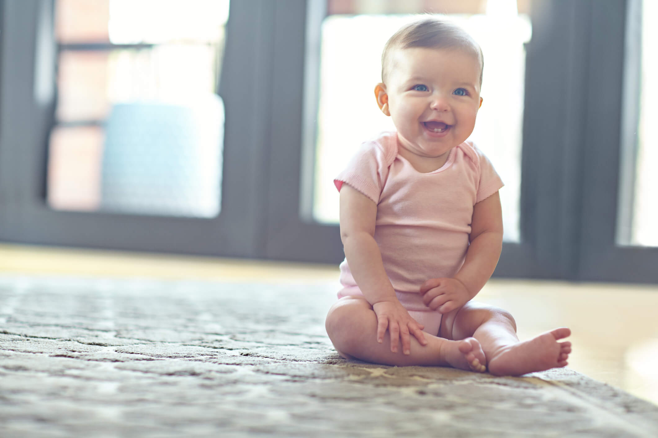 bebé feliz sentado en una alfombra