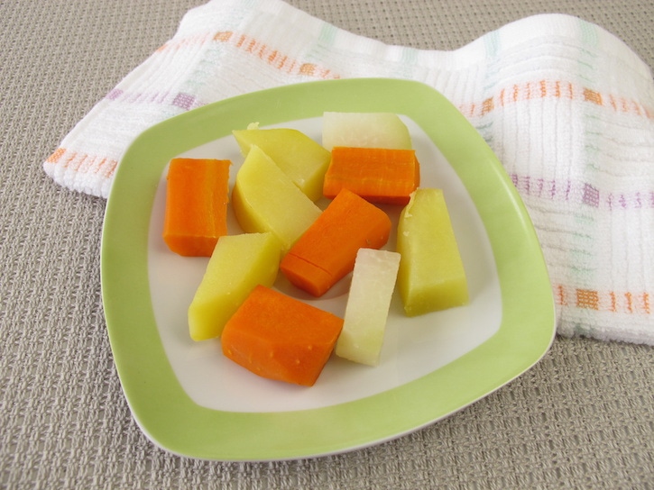 Trozos de verduras en un plato verde con blanco son un ejercicio para que tu bebe pruebe nuevas texturas y sabores