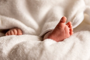 Pies de bebé saliendo de una cobija que su madre le llevó para después del parto