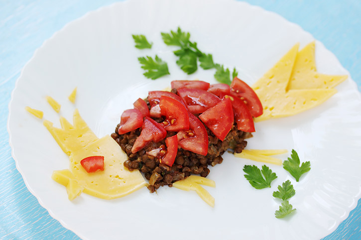 Plato de carne con tomate, queso y perejil como fuente de hierro y proteínas