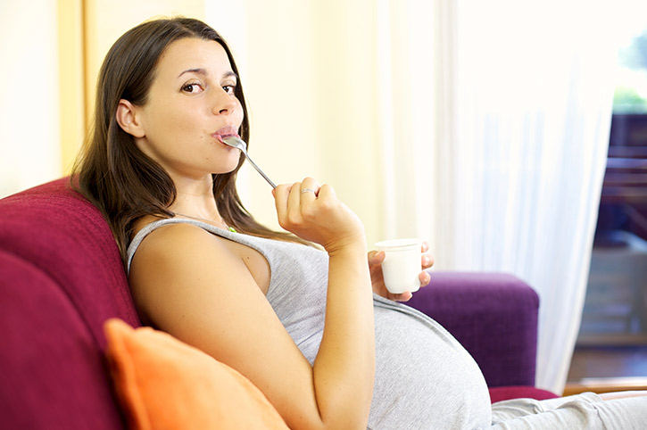 Madre embarazada comiendo con una cuchara alimentos que no contienen irritantes