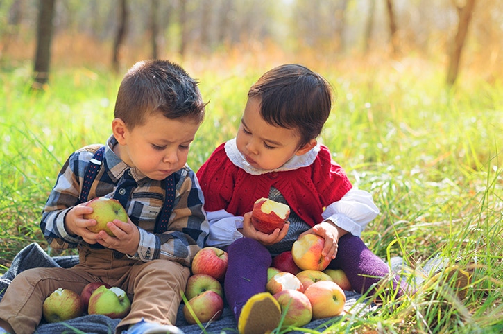 par de niños comiendo manzanas