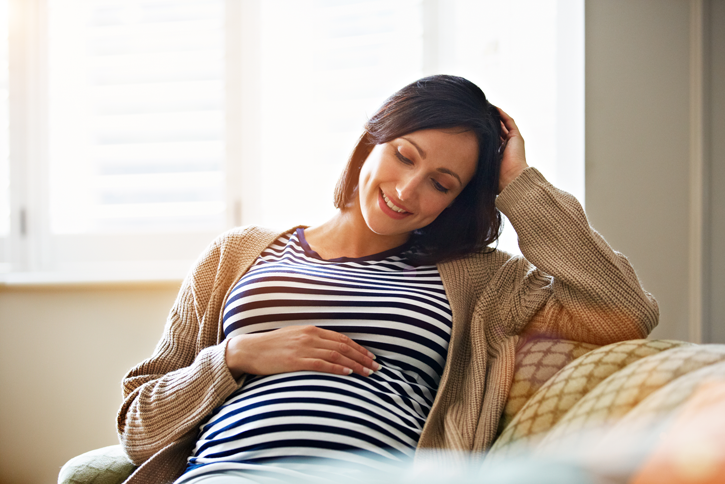 mujer embarazada sentada y con una mano sobre su vientre
