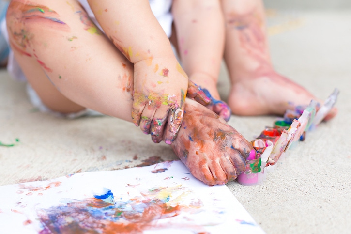 Pies y manos de bebe llenos de colores estimulando el sentido del tacto
