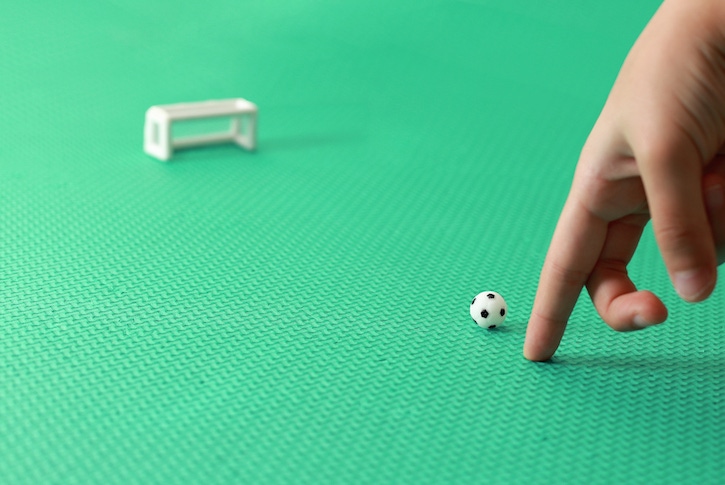 Manos de niño jugando futbolito para mejorar su concentración y moticidad fina