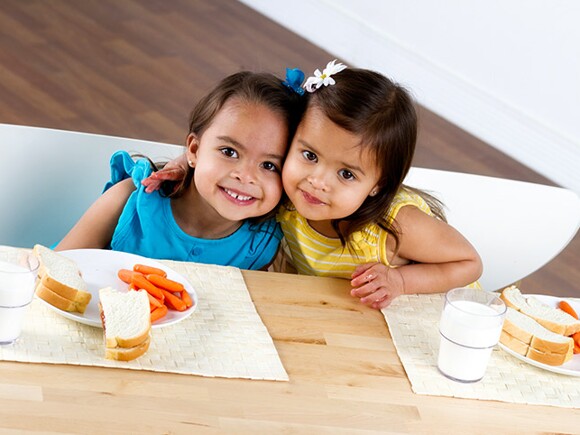 niñas abrazándose y comiendo despacio sus alimentos