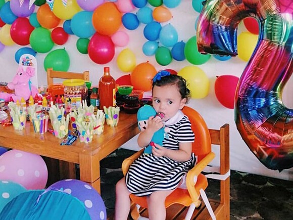 Pequeña sentada en una silla con globos a su alrededor disfrutando de Snacks para bebes