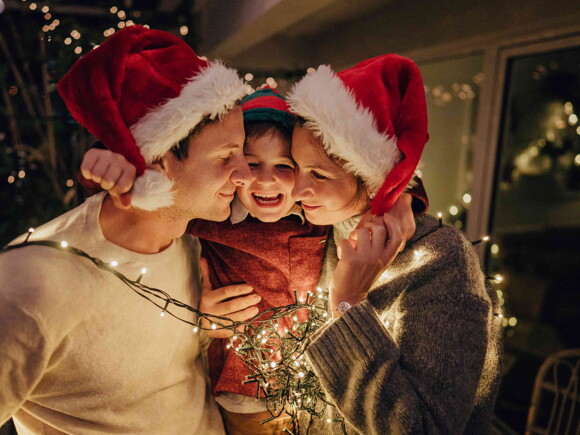 Niño con sus padres adornando árbol de navidad 