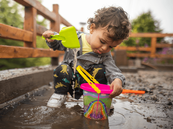 Niño con buen sistema inmunológico jugando con agua en el lodo