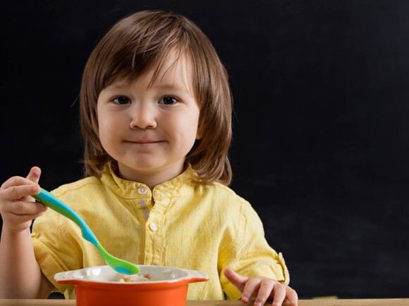 Niño sosteniendo una cuchara y un plato de cereal