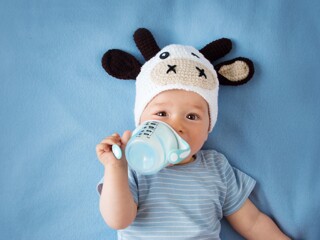 Peque de un año con sombrero de vaca tomando leche