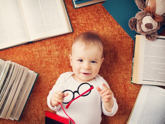 Niño de un año con anteojos rodeado de libros