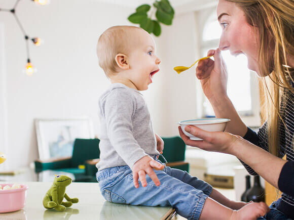 Bebé de 10 meses sentado comiendo con mamá