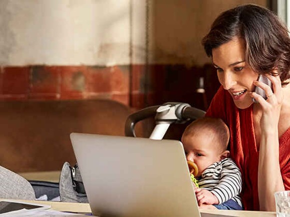Madre con bebe en la computadora buscando sitios de expertos en nutricion