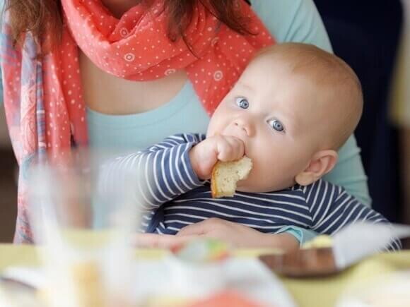 Bebé comiendo solito bajo la supervisión de su mamá