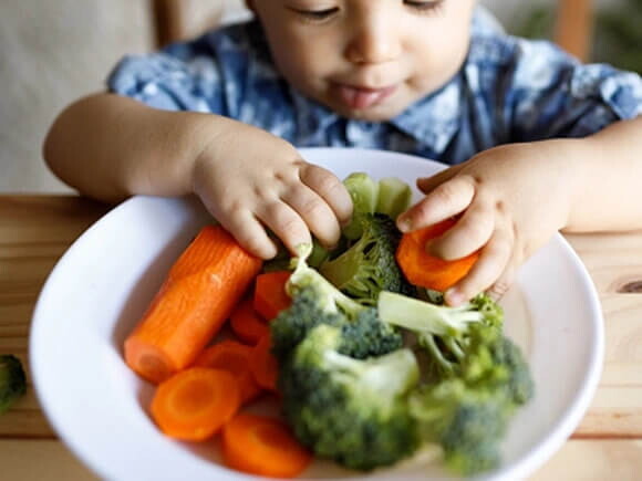 niño comiendo plato de verduras 