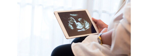 Mujer embarazada viendo un ultrasonido de su bebé a través de una tableta electrónica