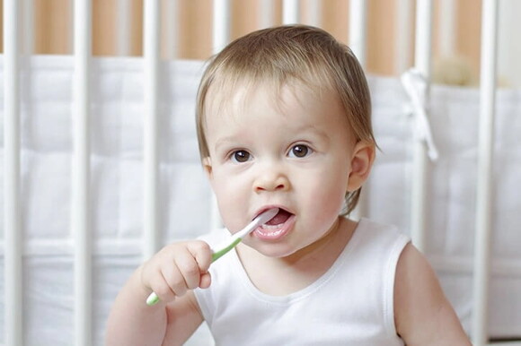 Bebé con un cepillo de dientes en la boca