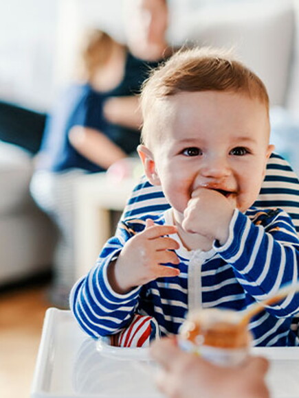 Bebé en su silla comiendo alimentos sólidos